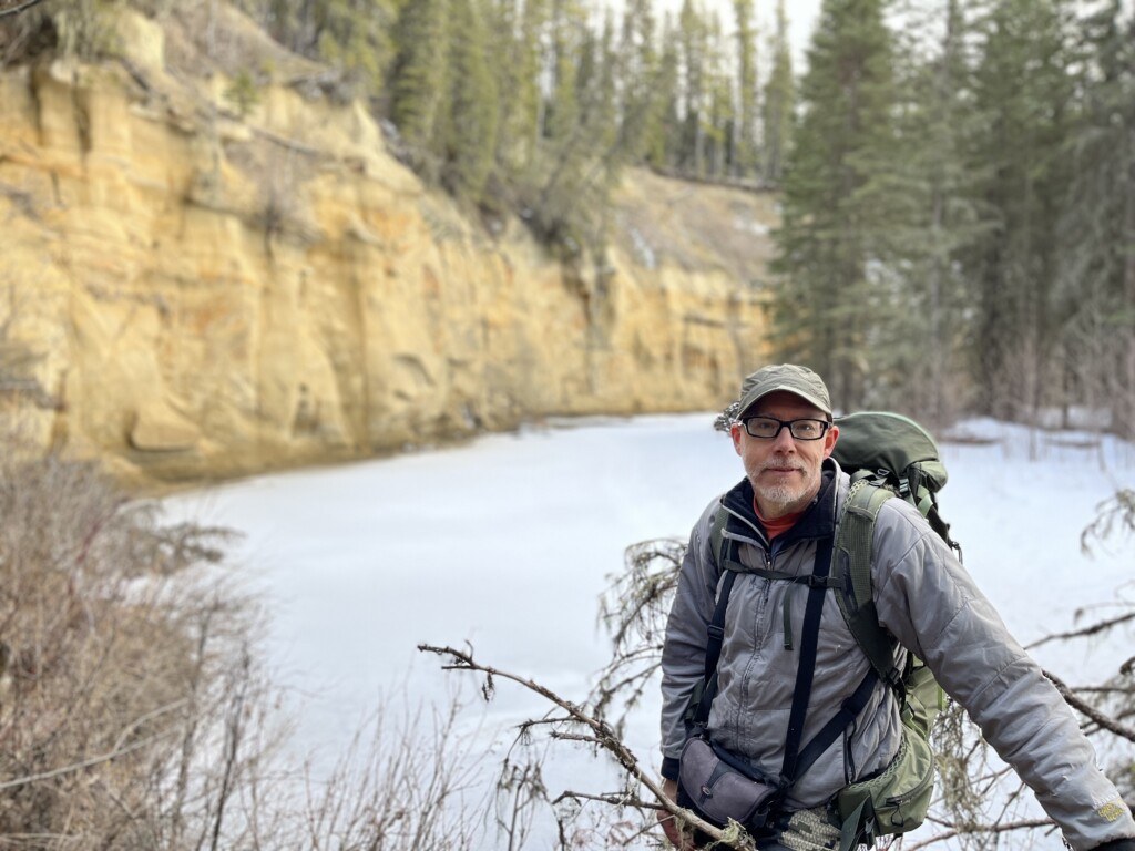 Joseph Litke poses at the base of a remote canyon cliff in northern Alberta. He is an expert tracker and wildlife specialist with Fiera Biological